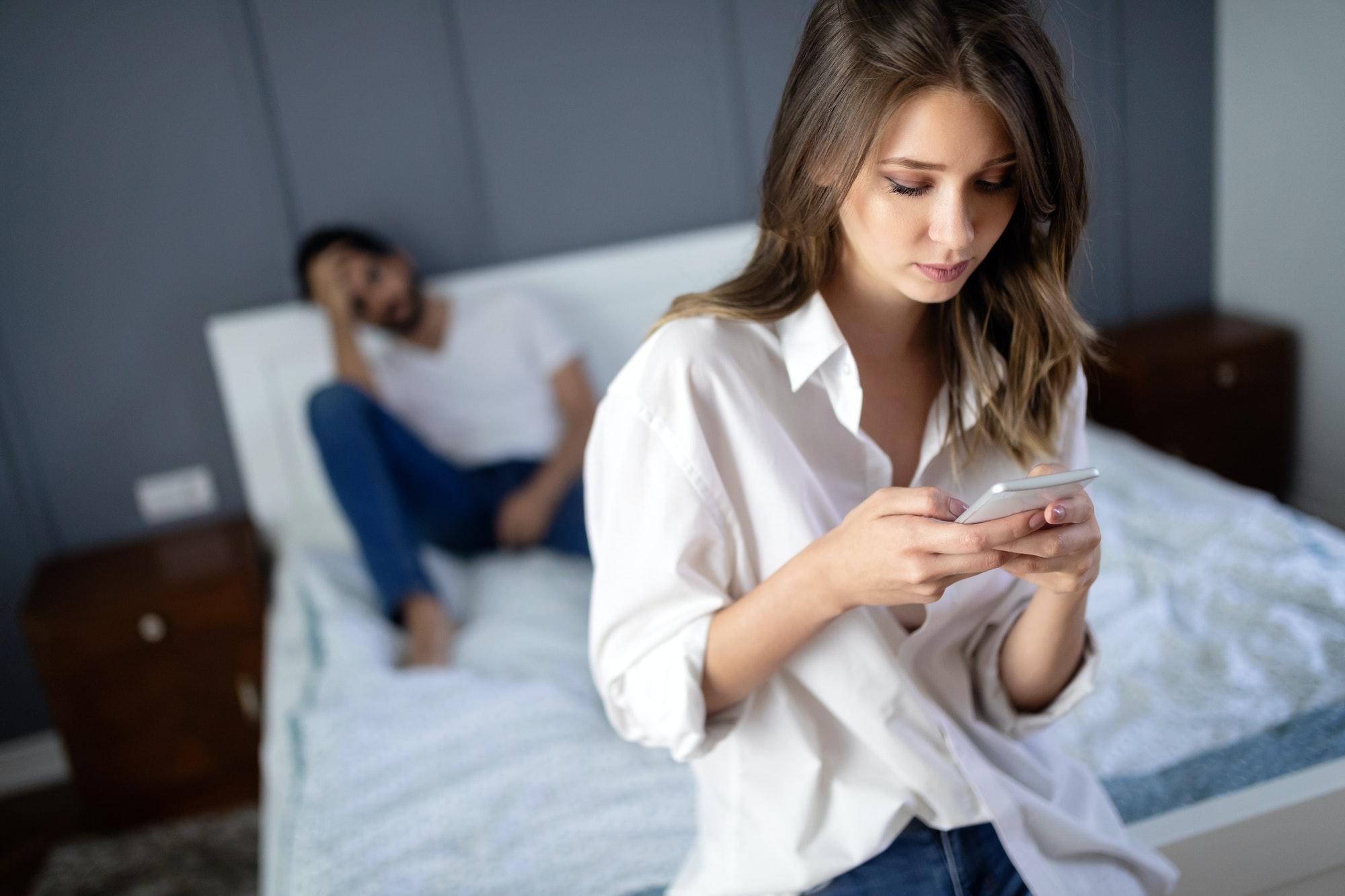 Unhappy couple ignoring each other using mobile phone