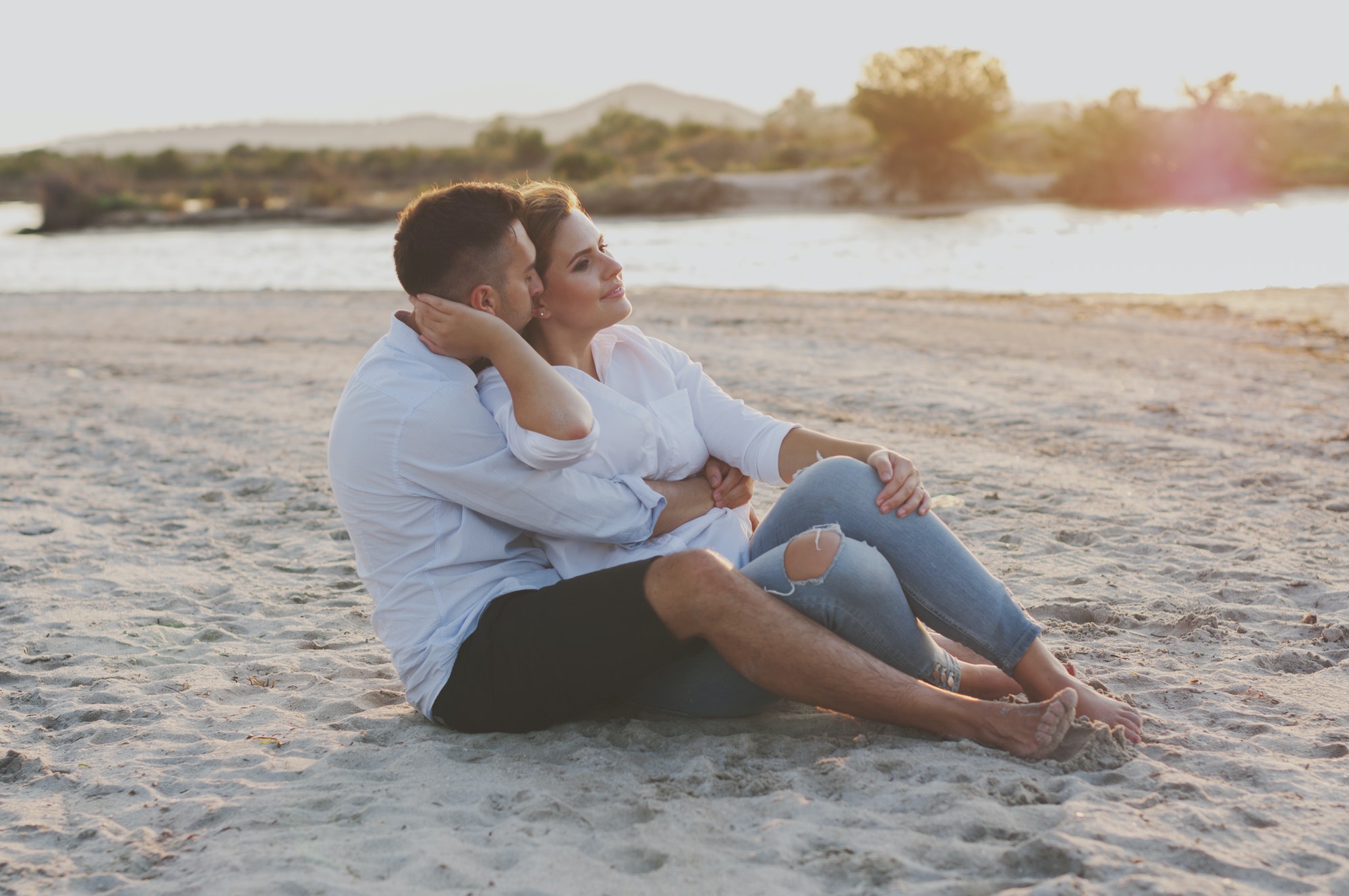 young happy couple sitting on the beach